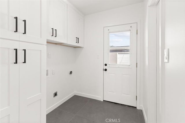 clothes washing area with cabinet space, electric dryer hookup, baseboards, and dark tile patterned flooring