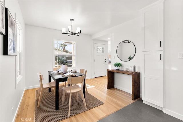 dining room featuring light wood finished floors, a notable chandelier, and baseboards