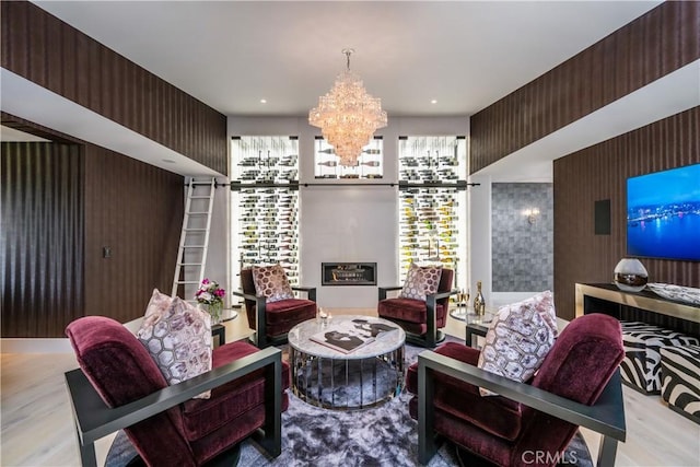 living area featuring a notable chandelier, wood walls, and wood finished floors