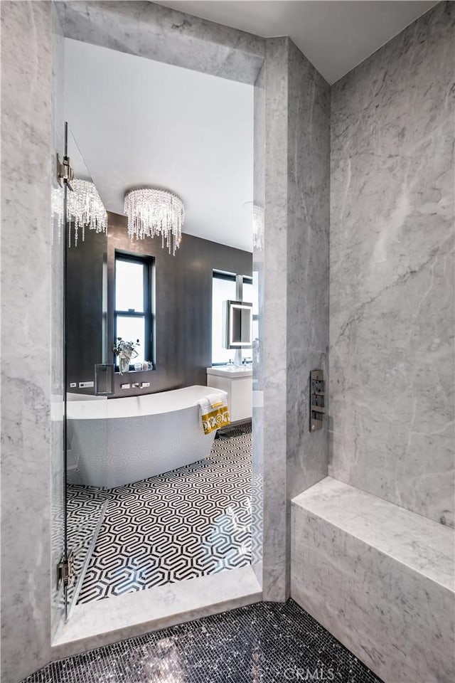 bathroom featuring tile patterned floors, a freestanding tub, and a notable chandelier