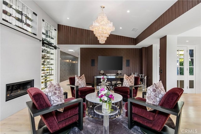 living room with visible vents, an accent wall, recessed lighting, an inviting chandelier, and wood finished floors