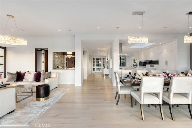 dining area featuring recessed lighting, a notable chandelier, and light wood-style flooring