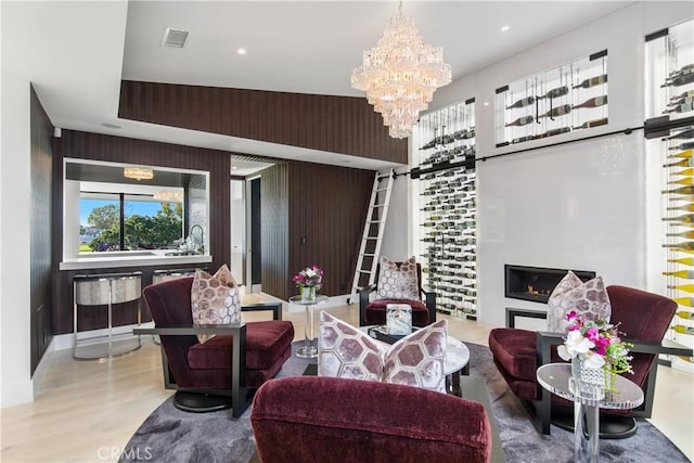 living room with a barn door, wood finished floors, visible vents, and a chandelier