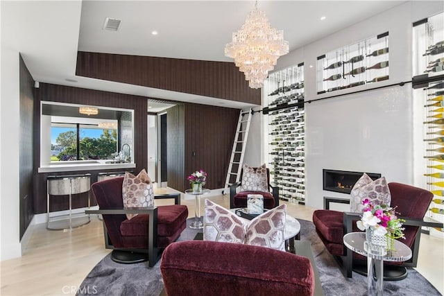 living room featuring visible vents, a barn door, an inviting chandelier, and wood finished floors