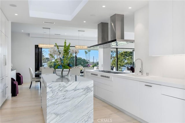 kitchen with cooktop, light wood-style flooring, white cabinetry, wall chimney exhaust hood, and modern cabinets