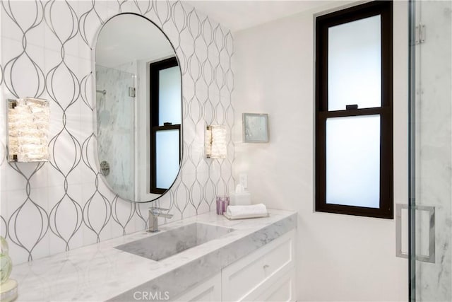 full bathroom with a marble finish shower, vanity, and decorative backsplash