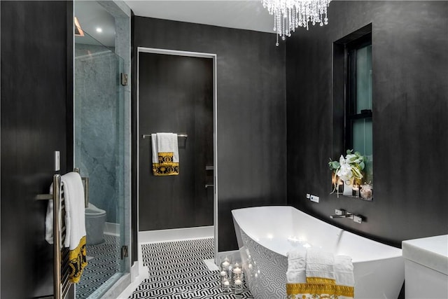 bathroom featuring toilet, a stall shower, an inviting chandelier, tile patterned flooring, and a soaking tub