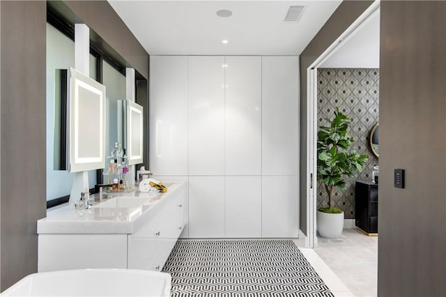 bathroom featuring tile patterned floors, visible vents, a freestanding tub, a sink, and double vanity