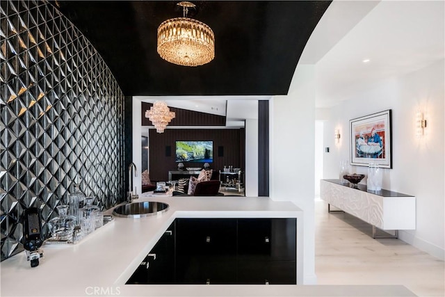 interior space with a sink, an inviting chandelier, wood finished floors, and light countertops