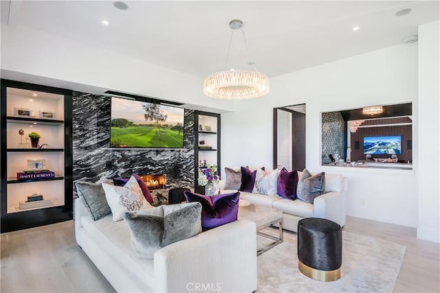 living room with a notable chandelier, built in shelves, and wood finished floors