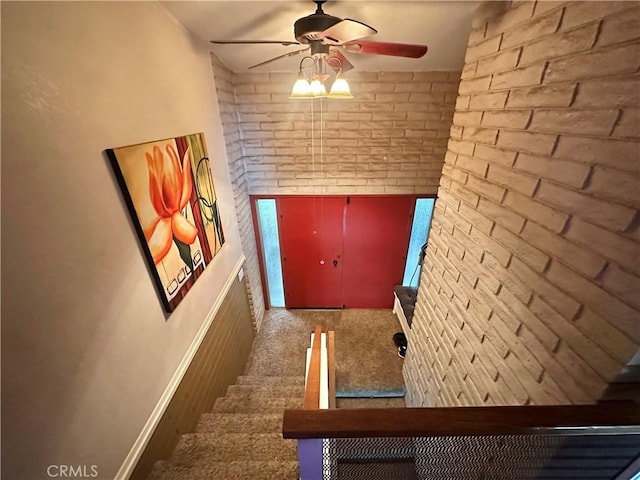 stairs featuring brick wall and ceiling fan