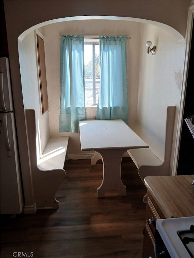 dining room featuring arched walkways and dark wood finished floors