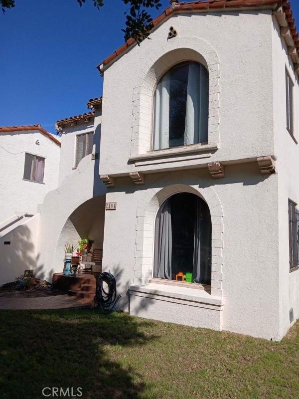 rear view of property with a tiled roof and stucco siding