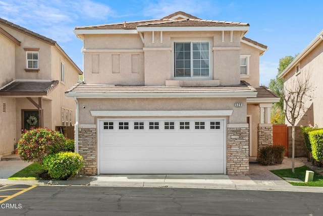 view of front of home with stucco siding, stone siding, a garage, and a tiled roof