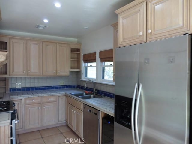 kitchen with a sink, stainless steel appliances, open shelves, and light brown cabinetry