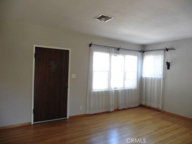 spare room featuring visible vents, baseboards, and wood finished floors