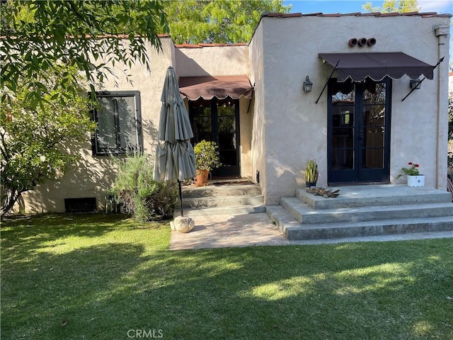 doorway to property featuring a yard and stucco siding