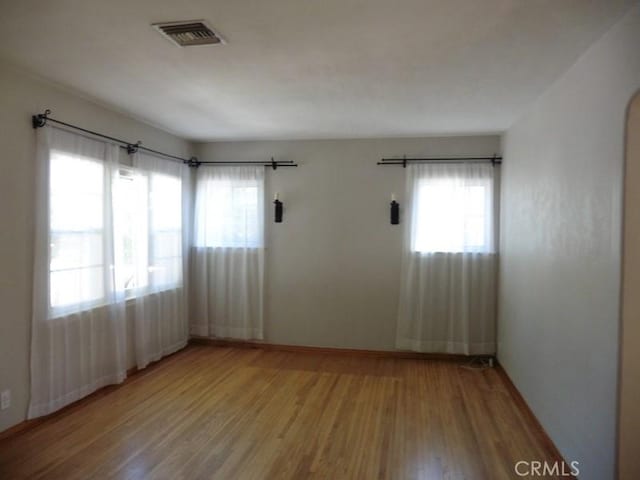 spare room with visible vents, baseboards, and wood finished floors