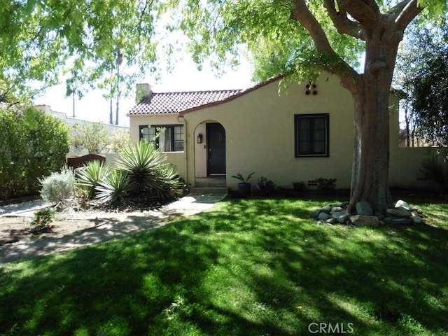 mediterranean / spanish house featuring stucco siding, a tiled roof, and a front yard