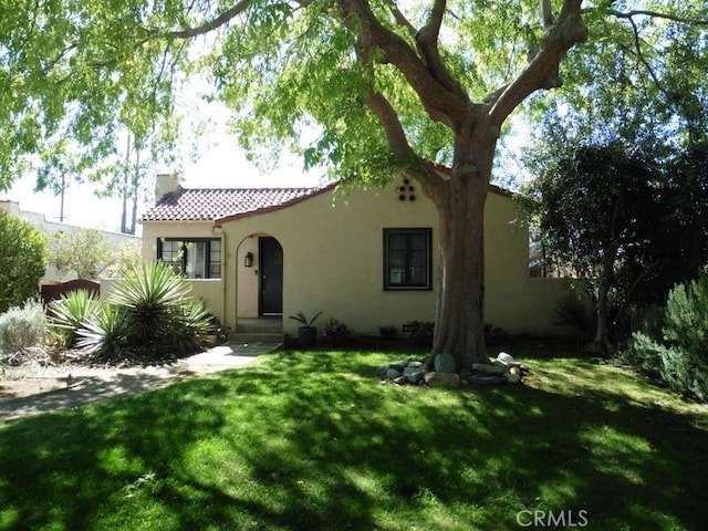 mediterranean / spanish home with stucco siding, fence, a front lawn, and a tile roof