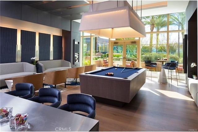 recreation room with a towering ceiling, expansive windows, wood finished floors, and billiards