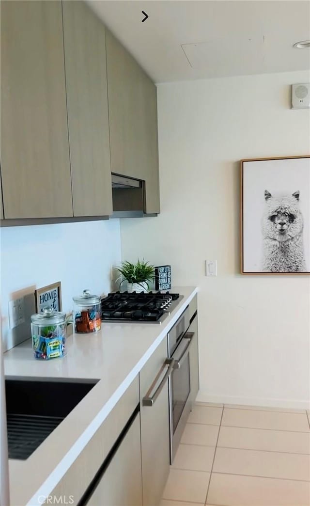 kitchen featuring light tile patterned flooring, stainless steel appliances, light countertops, and exhaust hood