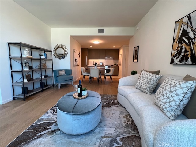 living room featuring visible vents, baseboards, and wood finished floors