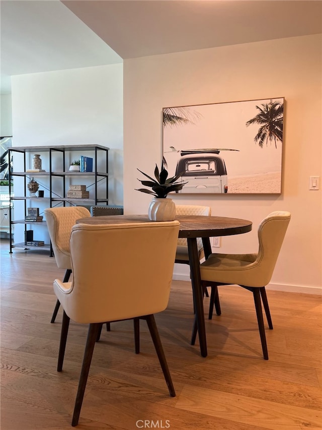 dining space featuring light wood-type flooring and baseboards