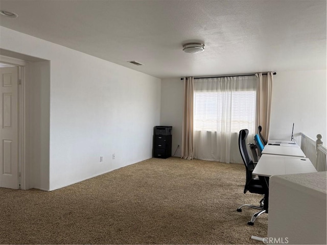 unfurnished office featuring visible vents, light carpet, and a textured ceiling