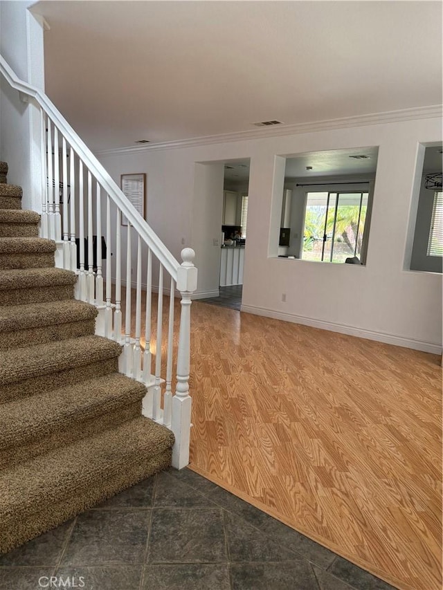 stairway featuring crown molding, wood finished floors, and baseboards