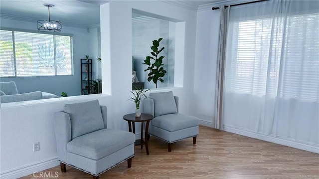 sitting room featuring baseboards, wood finished floors, and crown molding
