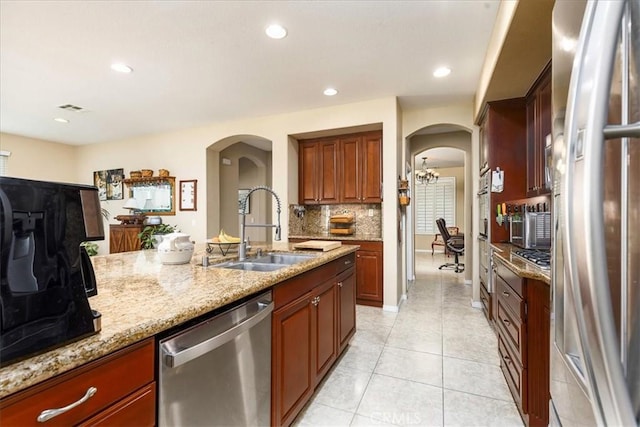 kitchen featuring light stone countertops, visible vents, arched walkways, a sink, and appliances with stainless steel finishes