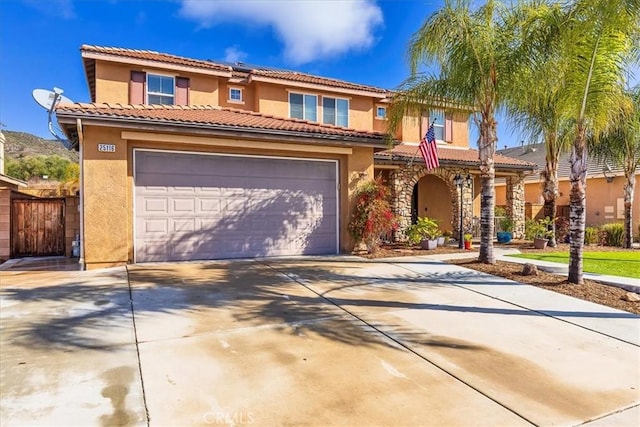 mediterranean / spanish-style house with stucco siding, concrete driveway, an attached garage, and a tile roof