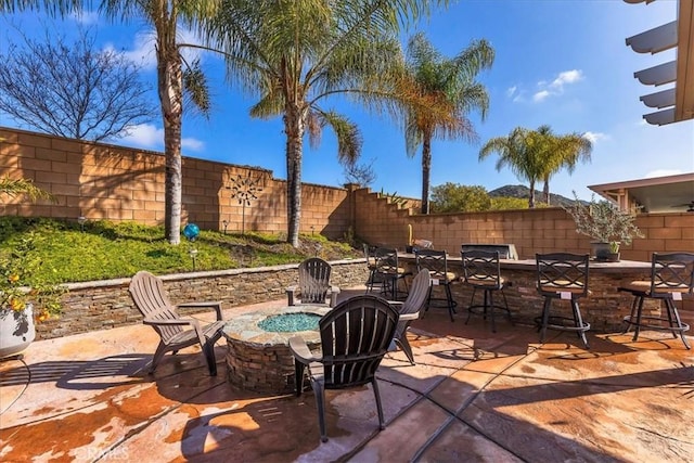 view of patio / terrace with a fenced backyard, a fire pit, and outdoor dry bar