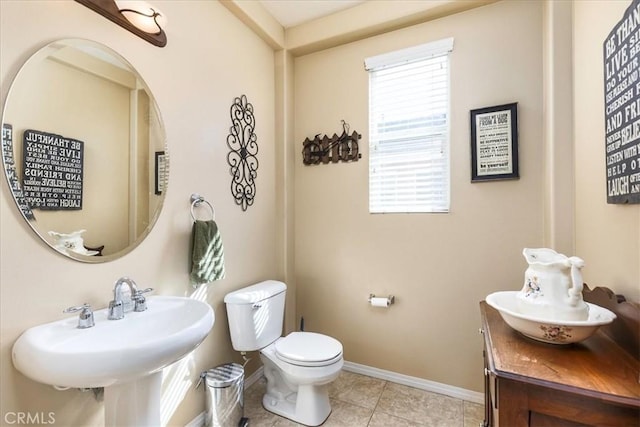 bathroom with tile patterned floors, toilet, baseboards, and a sink