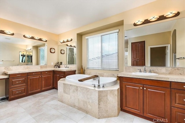 bathroom with tile patterned flooring, two vanities, a garden tub, and a sink