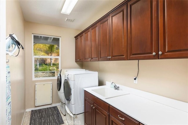 laundry room with visible vents, washing machine and dryer, light tile patterned floors, cabinet space, and a sink