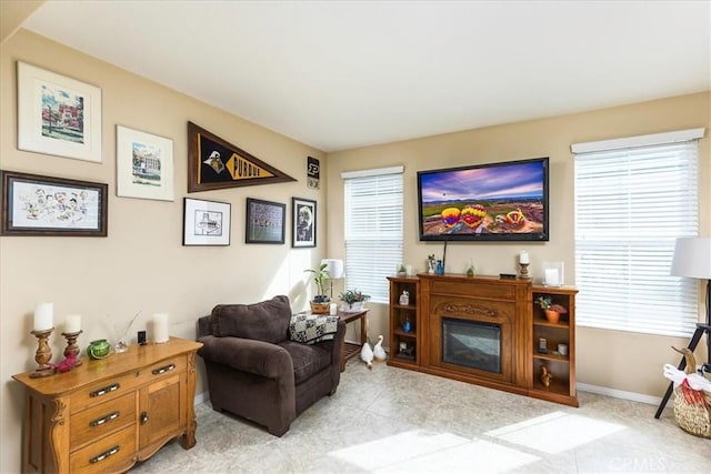 living area with light tile patterned flooring, baseboards, and a wealth of natural light