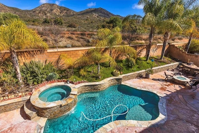 view of pool featuring a patio, a fenced backyard, a mountain view, and a pool with connected hot tub