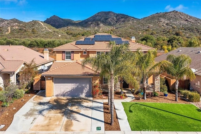 mediterranean / spanish house featuring solar panels, stucco siding, a garage, a tile roof, and a mountain view