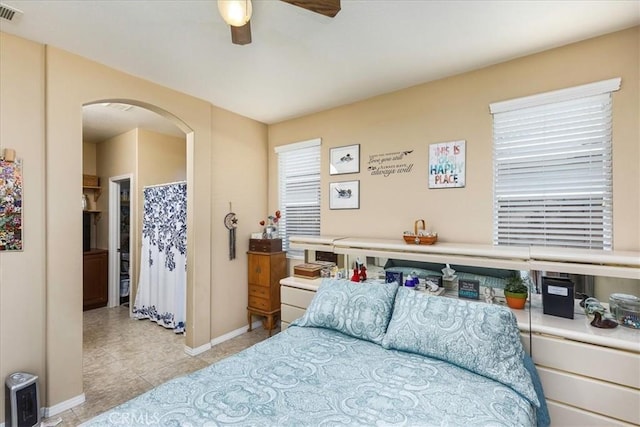 bedroom with visible vents, arched walkways, baseboards, and ceiling fan