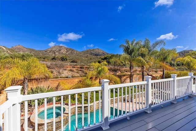 wooden deck featuring a fenced in pool, a mountain view, and an in ground hot tub