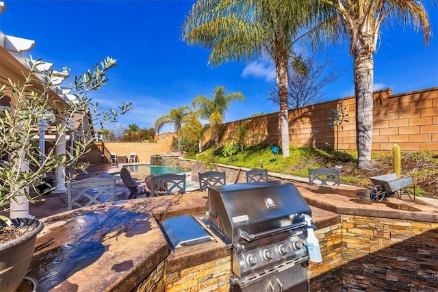 view of patio with exterior kitchen, a fenced backyard, a fenced in pool, and grilling area