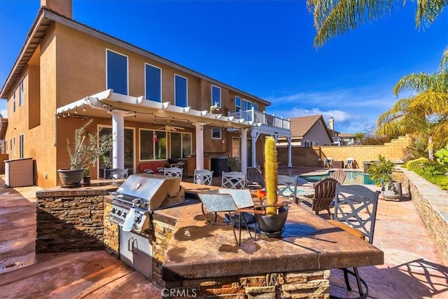 rear view of house with fence, an outdoor kitchen, stucco siding, a chimney, and a patio area