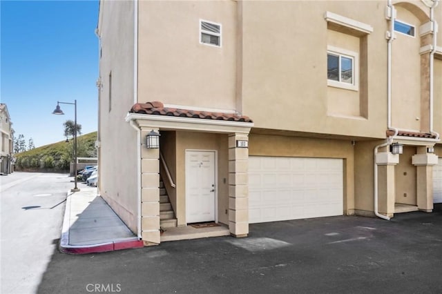 2810 Green River Rd Unit 103, Corona, CA 92882 - townhome / multi-family property with stucco siding, an attached garage, driveway, and a tiled roof