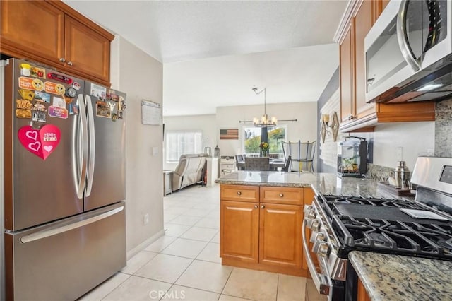 2810 Green River Rd Unit 103, Corona, CA 92882 - kitchen with stainless steel appliances, brown cabinets, a chandelier, a peninsula, and light tile patterned flooring