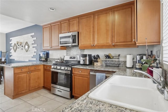2810 Green River Rd Unit 103, Corona, CA 92882 - kitchen featuring stainless steel appliances, a sink, brown cabinets, light tile patterned floors, and a peninsula
