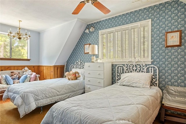 bedroom featuring a wainscoted wall, ceiling fan with notable chandelier, and wallpapered walls