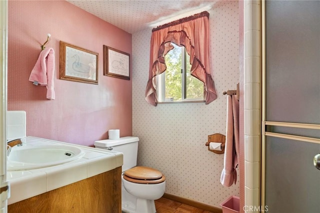 full bath with wallpapered walls, toilet, vanity, and a shower