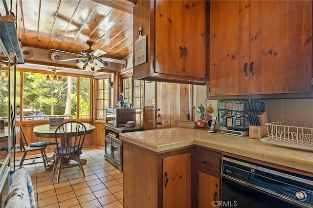 kitchen featuring black dishwasher, brown cabinetry, backsplash, and light tile patterned flooring